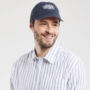 Mann med caps i marine navy farge, og justering bak.